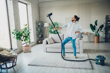 Young man creatively using a vacuum cleaner while enjoying leisure activity in a modern...