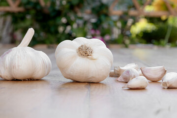 Fresh garlic bulbs and cloves arranged on wooden surface in a bright and natural setting.