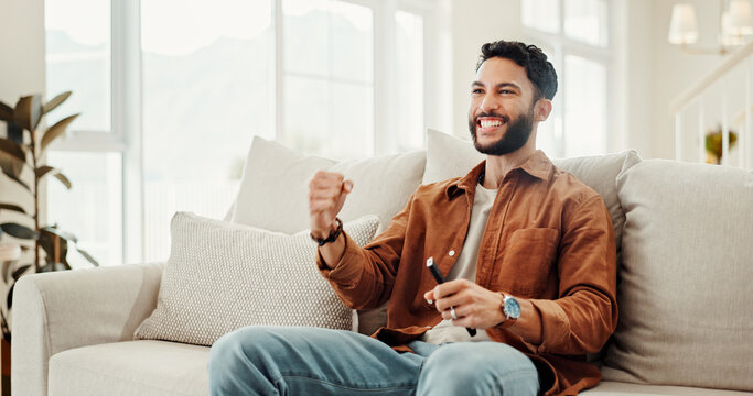 Fist pump, support and television with man on sofa in home living room for subscription service. Celebration, streaming and watching tv with sports fan cheering or celebrating success in apartment