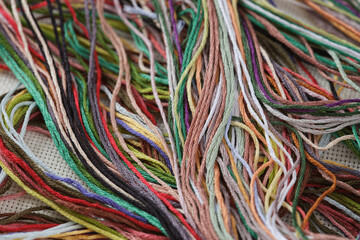 A background of colorful cross stitch embroidery threads. Close up.