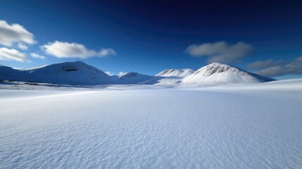 Snowy mountain range panorama under a vibrant blue sky.  