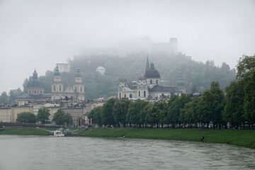 Landscape with Hohensalzburg castle on Festung mountain in Salzburg, Austria view from the Salzach river in overcast foggy weather