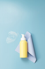 Yellow bottle with a dispenser, paper and a smear of gel on a blue background.