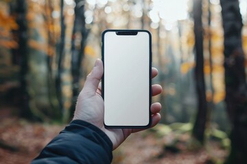 Hand holding blank smartphone screen in autumn forest, symbolizing digital connection or detox. Perfect for tech promotions, outdoor lifestyle, and environmental themes.