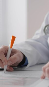 A dedicated medical professional in a clean white coat writes notes on a clipboard and types on a laptop, demonstrating a key healthcare documentation process in a clinical setting