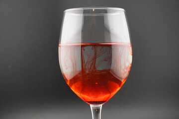 Colored water dropping into a wine glass filled with water.