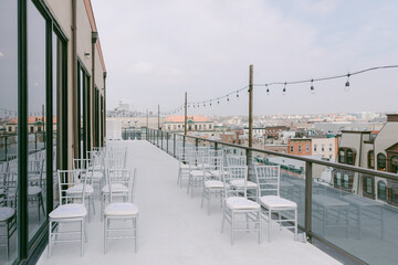 Rooftop venue with empty chairs overlooking city skyline during daytime for events or gatherings