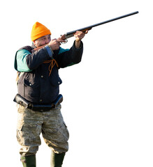 Mature hunter man holding a shotgun and walking through a field