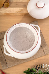 White ceramics dish with handles and lid for baking stands on kitchen table