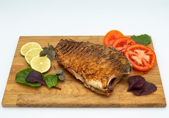 Fried crucian carp served with vegetables, lemon and herbs. Fried fish.