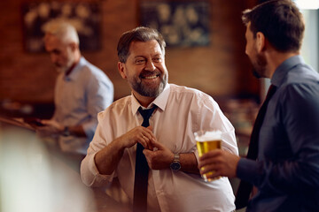 Happy mature businessman talking to colleague in pub.