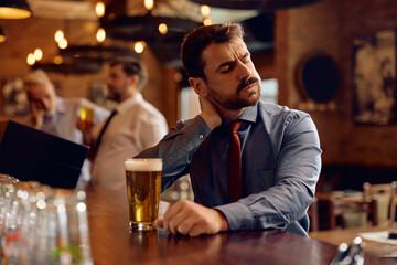 Exhausted businessman drinking beer in pub after work.