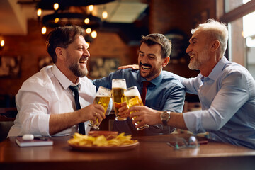 Cheerful entrepreneurs toasting while celebrating after successful business meeting in pub.
