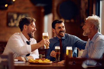 Happy entrepreneurs talking while drinking beer after business meeting in pub.