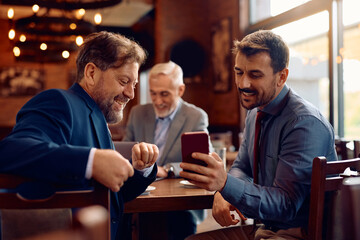 Happy businessmen using smart phone in cafe.