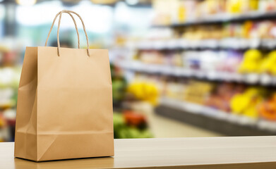 A paper shopping bag placed on a counter with shelves of products blurred in the background.
