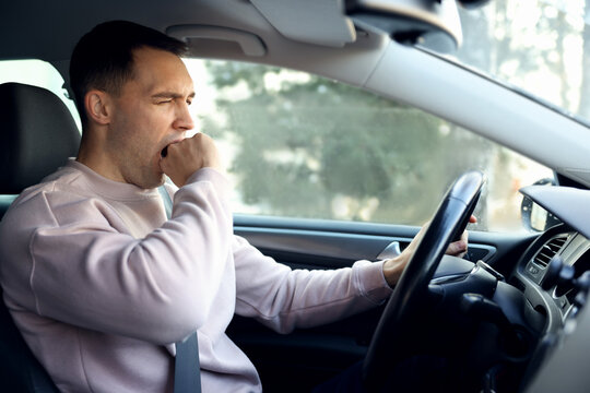 Sleepy driver yawning in his modern car