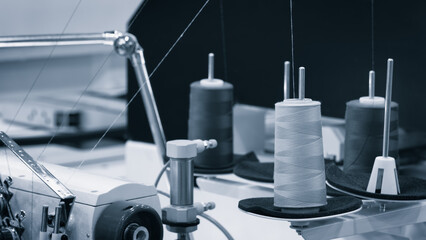 A sewing machine with a spool of thread on it. The spool is white and the machine is black