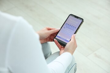 Menstruation. Woman using period calendar application on smartphone indoors, closeup