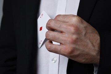 Illusionist hiding playing card behind jacket lapel, closeup