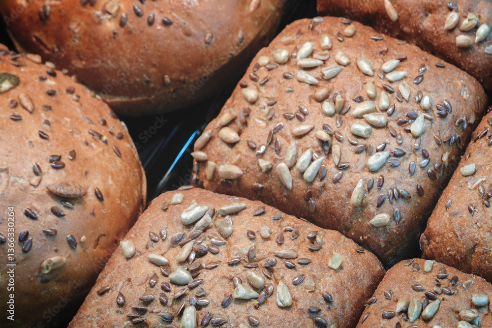Poster A close up of several breads with seeds on top. The breads are all different sizes and shapes