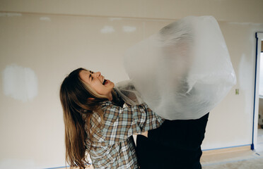 A husband playfully throws a bag over his wife's head and they laugh.