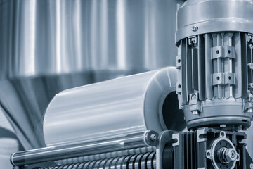 A machine with a roll of polyethylene plastic film on it. The machine is in a factory. industrial...