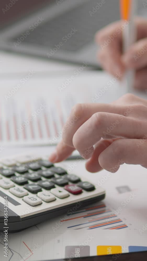 Poster A skilled professional uses a calculator while reviewing financial documents and charts on an organized desk, demonstrating productivity and complex analytical tasks in their work