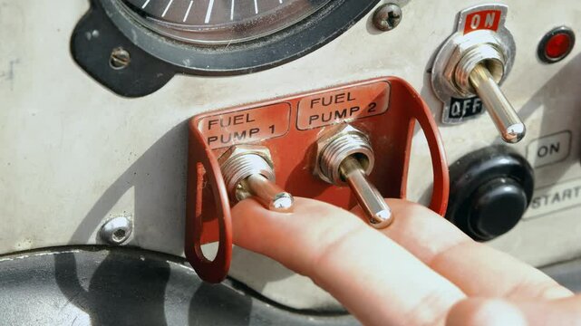 The pilot of an airplane or helicopter turns on the fuel pumps before starting the engine. Close-up of toggle switch on dashboard