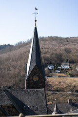 A steeple with a clock on top of a stone church building against the blue sky. Concept of a...