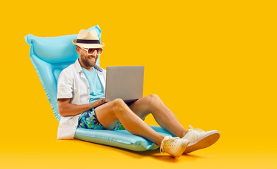 Happy man looking for sea tickets and booking hotel while sitting with laptop on inflatable...