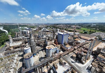 Visão aérea grande angular mostra indústria de papel e celulose em produção, com chaminés e...