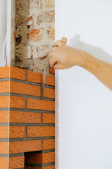 A young man makes brickwork on the chimney of a fireplace.