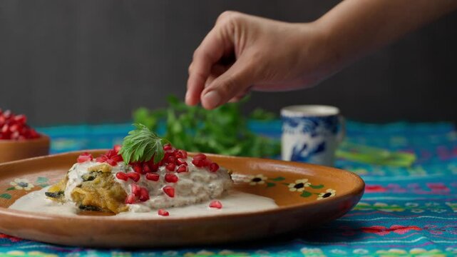 Mexican chile en nogada on a table with a blue tablecloth and garnished with a parsley leaf