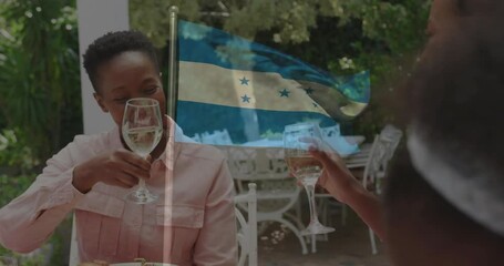 Waving Honduras flag, people eating meal together, smiling at outdoor gathering - Powered by Adobe