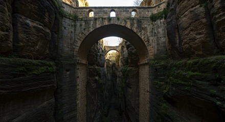 Magnificent stone bridge structure spanning a dramatic subterranean chasm landscape