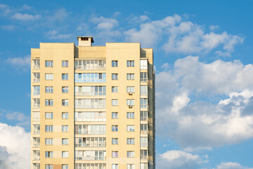 this image features a modern high-rise residential building with a beige facade, large windows, and...