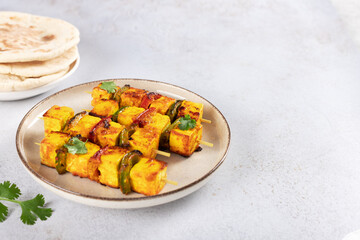 Fried Indian paneer cheese with pepper on white background. Paneer Tikka. Indian food. Copy space.
