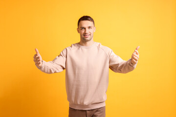 Cheerful man welcoming guests on orange background