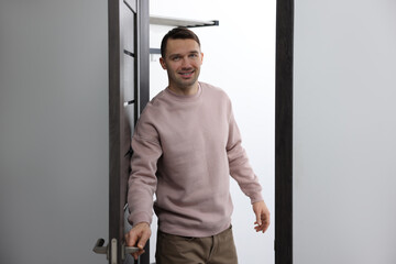 Cheerful man welcoming guests to his apartment
