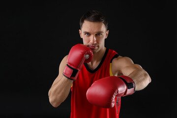 Man in boxing gloves fighting on black background