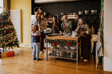 A White family spending quality time together in the kitchen during the holiday season, baking cookies, decorating, and enjoying the festive atmosphere around a Christmas tree with love and laughter.