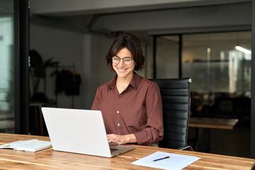 Smiling Hispanic businesswoman company employee sitting at work desk, professional female hr...