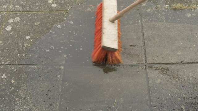 red broom standing on freshly washed garden tiles