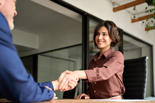 Smiling female hr hiring recruit at job interview, insurance agent, lawyer making contract deal at work with business handshake. Happy young business woman bank manager handshaking client at meeting.