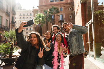 A multinational group of young people in a vibrant city, smiling, making peace signs, and taking a...