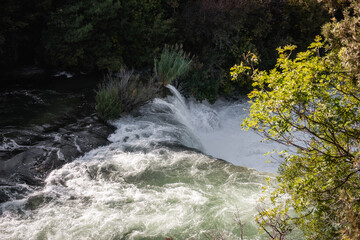 Water flows down a waterfall in Krka national park, Croatia, creating white water rapids as it...