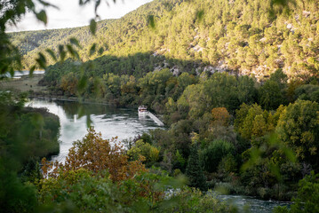 Tranquil scene in Krka national park, Croatia, featuring a tourist boat resting on the serene Krka...