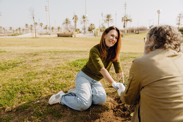 Couple, woman sitting and smiling while looking at man holding hands while sitting next to her,...