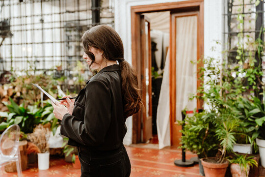 Female organizer standing and checking the program while looking at the clipboard, in the establishment, before the wedding ceremony